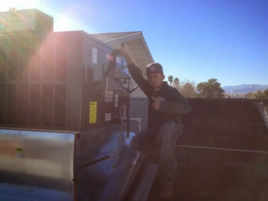 HVAC technician performing AC Tune-Up on a rooftop unit in Rosedale